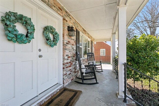 property entrance featuring brick siding and a porch