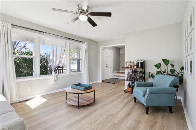 living area featuring ceiling fan, visible vents, light wood-type flooring, and baseboards