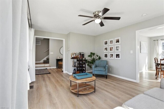 sitting room featuring stairway, visible vents, baseboards, ceiling fan, and light wood-type flooring