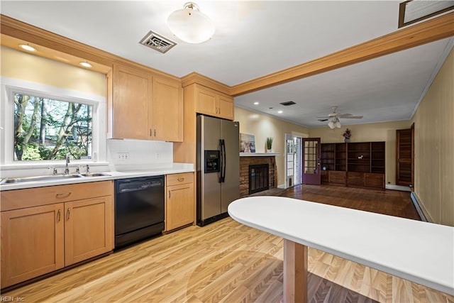 kitchen with visible vents, stainless steel refrigerator with ice dispenser, a sink, a brick fireplace, and dishwasher