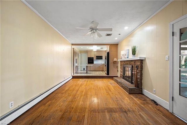 unfurnished living room featuring a baseboard radiator, a fireplace, ceiling fan, crown molding, and light wood-type flooring