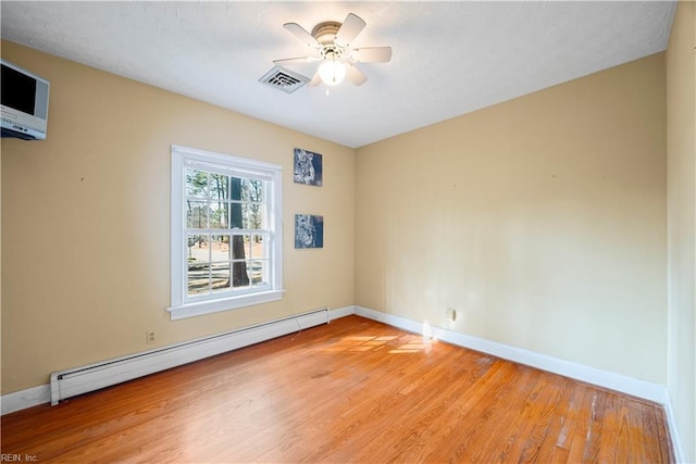 empty room featuring a ceiling fan, visible vents, baseboard heating, and baseboards