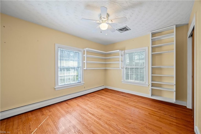 unfurnished room with light wood-type flooring, visible vents, built in features, a baseboard radiator, and ceiling fan