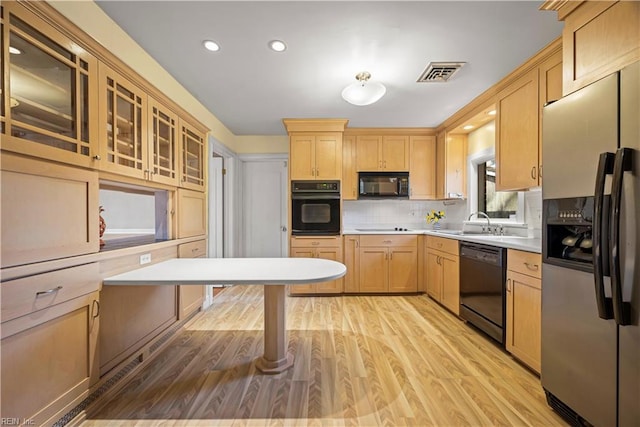 kitchen with light brown cabinets, visible vents, black appliances, light wood-style floors, and backsplash