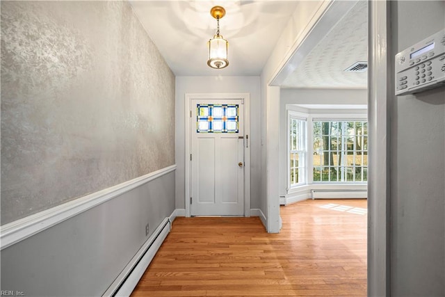 doorway to outside featuring a baseboard heating unit, light wood-style flooring, baseboards, and visible vents