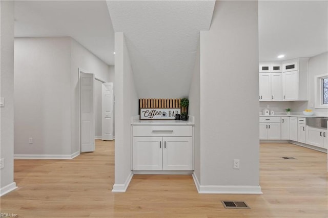 interior space with visible vents, white cabinets, light countertops, and light wood finished floors