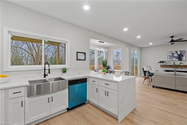 kitchen with light wood-type flooring, a sink, a peninsula, white cabinets, and dishwashing machine