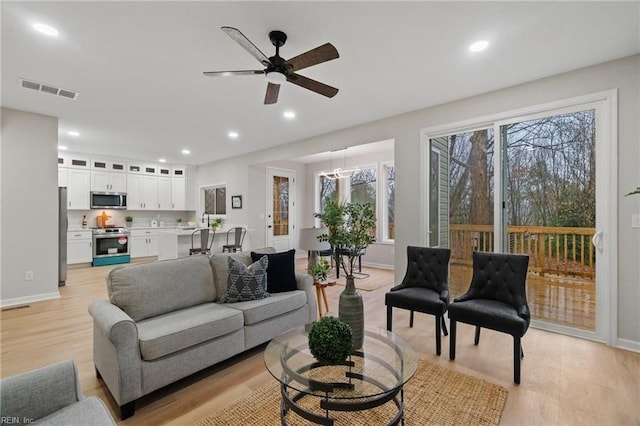 living area with light wood finished floors, visible vents, and recessed lighting