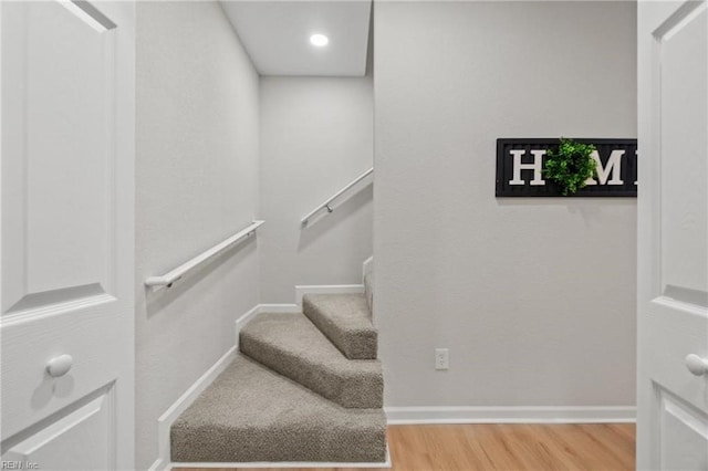 staircase featuring wood finished floors and baseboards