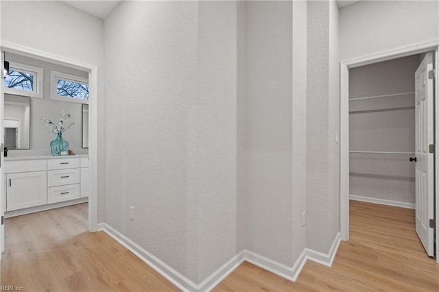 corridor with baseboards and light wood finished floors