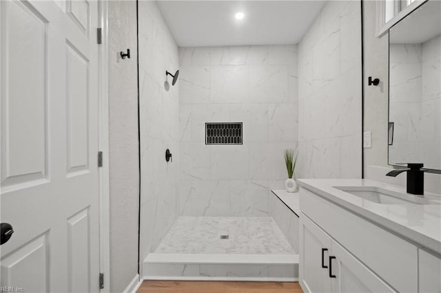 bathroom featuring a marble finish shower, vanity, and wood finished floors