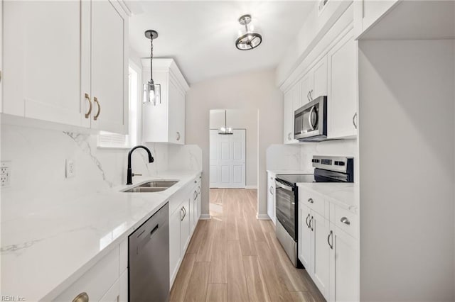 kitchen featuring white cabinets, light stone counters, appliances with stainless steel finishes, and a sink