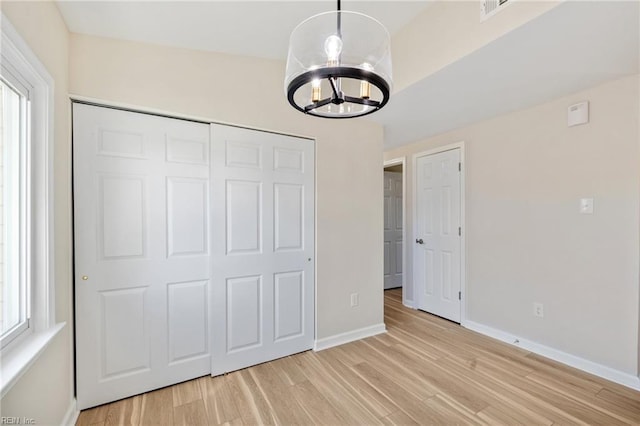 unfurnished bedroom featuring a closet, multiple windows, baseboards, and light wood finished floors