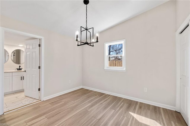 unfurnished dining area featuring a chandelier, baseboards, light wood finished floors, and a sink