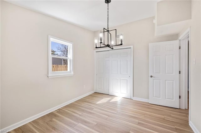 unfurnished dining area featuring light wood-style flooring, baseboards, and a chandelier