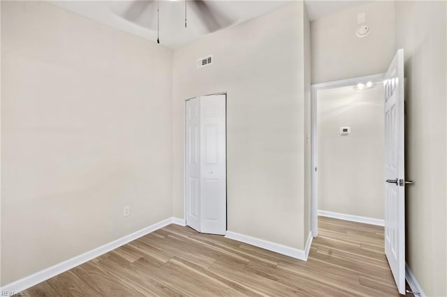 unfurnished bedroom featuring baseboards, visible vents, light wood finished floors, ceiling fan, and a closet