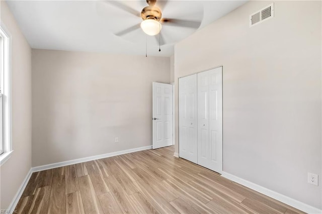 unfurnished bedroom featuring light wood-style flooring, baseboards, visible vents, and a closet