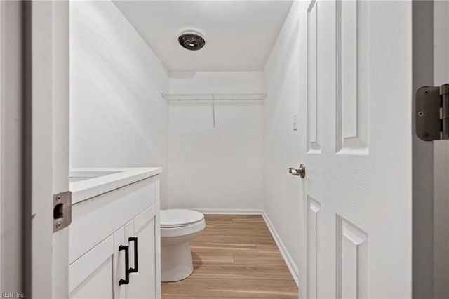 bathroom with toilet, vanity, baseboards, and wood finished floors