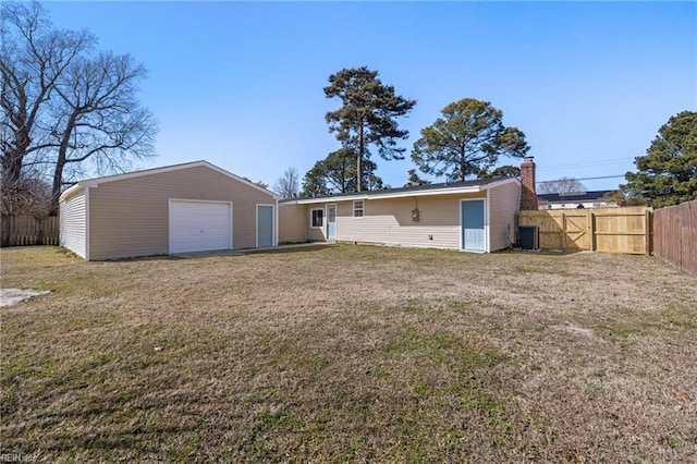 rear view of property featuring a garage, cooling unit, a yard, and fence