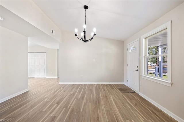 interior space with a notable chandelier, light wood-style flooring, visible vents, and baseboards