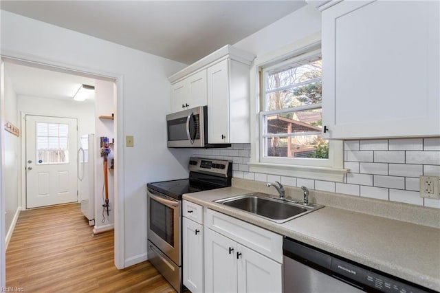 kitchen featuring a wealth of natural light, appliances with stainless steel finishes, white cabinetry, and a sink