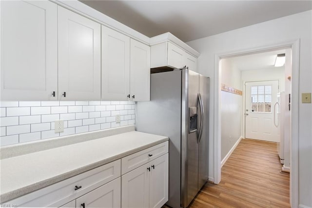 kitchen with light wood-style flooring, tasteful backsplash, white cabinetry, stainless steel fridge with ice dispenser, and light countertops