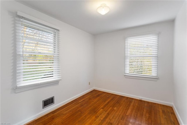 empty room featuring visible vents, baseboards, and wood-type flooring