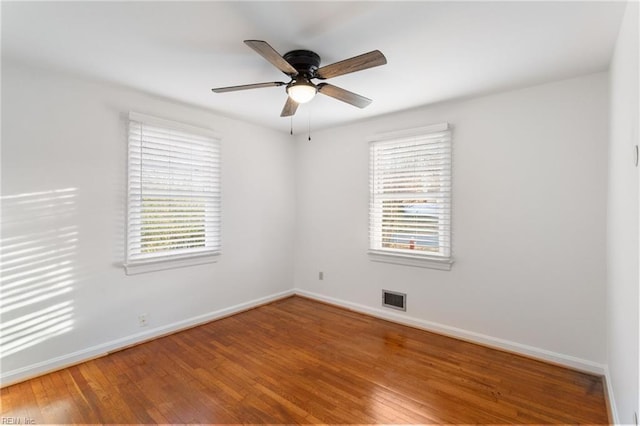 unfurnished room with visible vents, plenty of natural light, baseboards, and wood finished floors