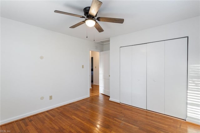 unfurnished bedroom featuring hardwood / wood-style flooring, baseboards, a closet, and ceiling fan