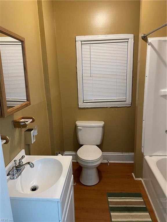 bathroom with toilet, wood finished floors, washtub / shower combination, baseboards, and vanity