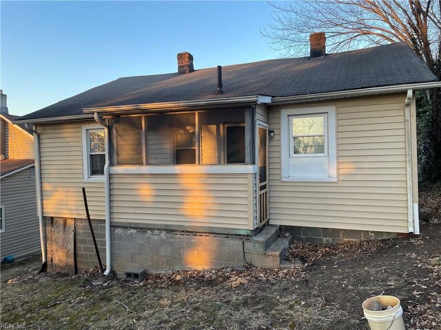 back of property with a chimney and a shingled roof