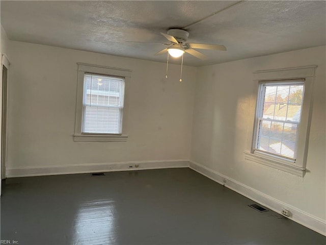 empty room with visible vents, ceiling fan, a textured ceiling, and baseboards