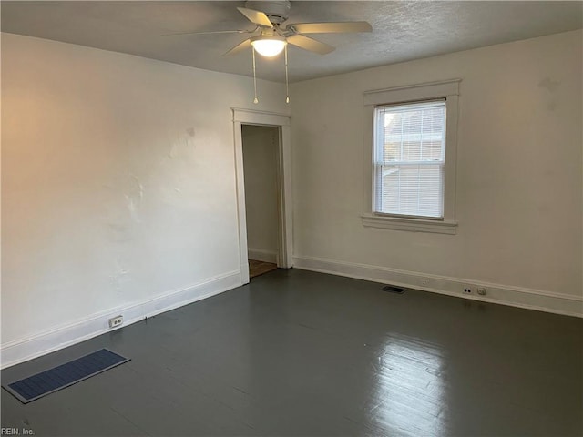 empty room with visible vents, ceiling fan, a textured ceiling, and baseboards