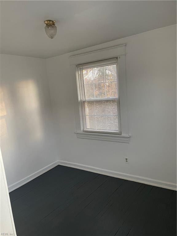 spare room featuring dark wood finished floors and baseboards