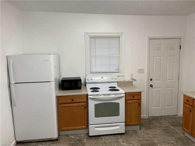 kitchen with brown cabinetry, white appliances, and light countertops