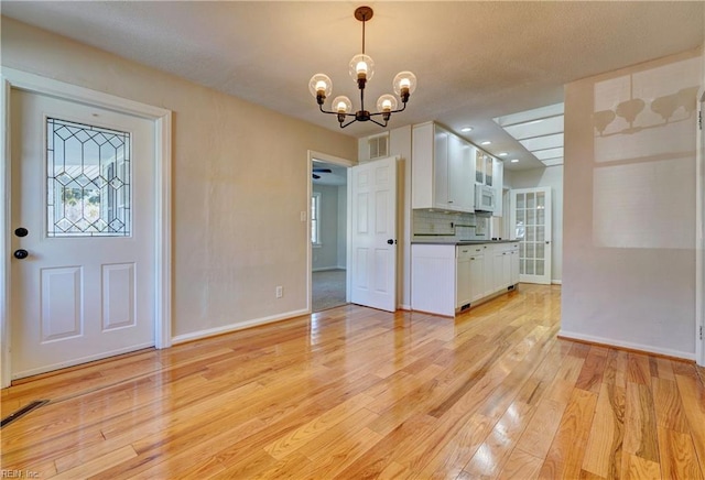 kitchen with visible vents, backsplash, dark countertops, white cabinetry, and light wood finished floors