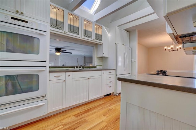 kitchen featuring white appliances, light wood-type flooring, dark countertops, a warming drawer, and tasteful backsplash