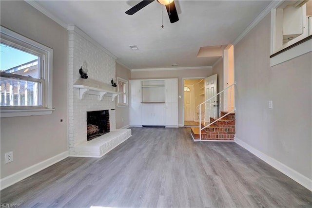 unfurnished living room featuring a fireplace, crown molding, baseboards, and wood finished floors