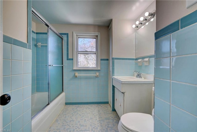 bathroom featuring tile patterned floors, toilet, tile walls, enclosed tub / shower combo, and vanity