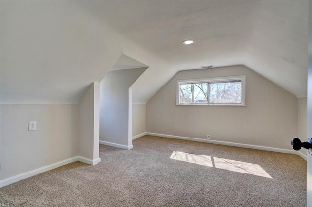 additional living space featuring carpet flooring, visible vents, lofted ceiling, and baseboards