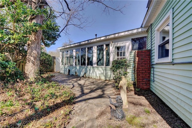 exterior space featuring a patio area, fence, and a sunroom