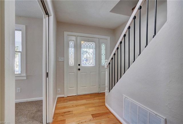 entryway featuring visible vents, baseboards, a healthy amount of sunlight, and stairway