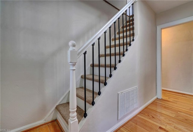 stairway featuring wood finished floors, visible vents, and baseboards