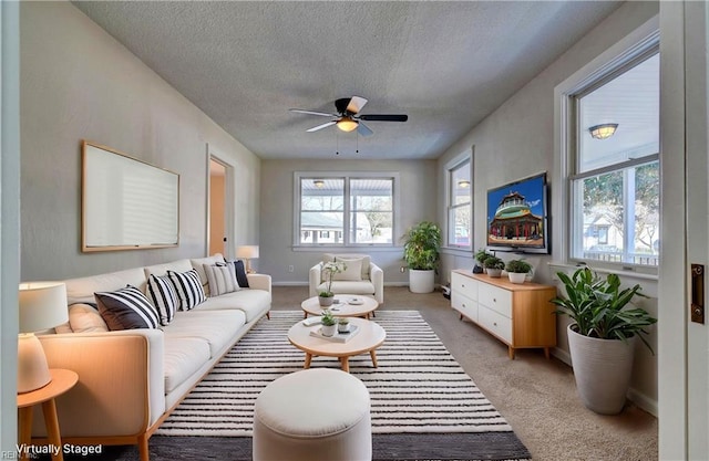 living area with a ceiling fan, light colored carpet, baseboards, and a textured ceiling