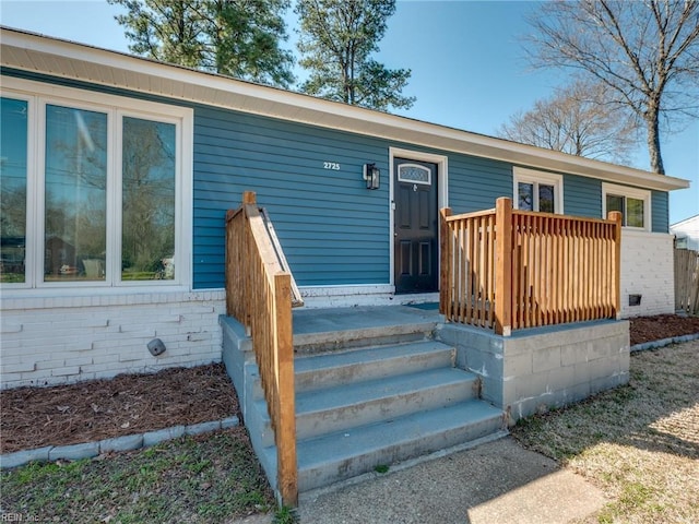 entrance to property with brick siding and a wooden deck