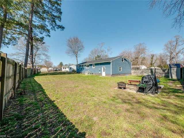 view of yard with an outbuilding, a shed, a fire pit, and a fenced backyard