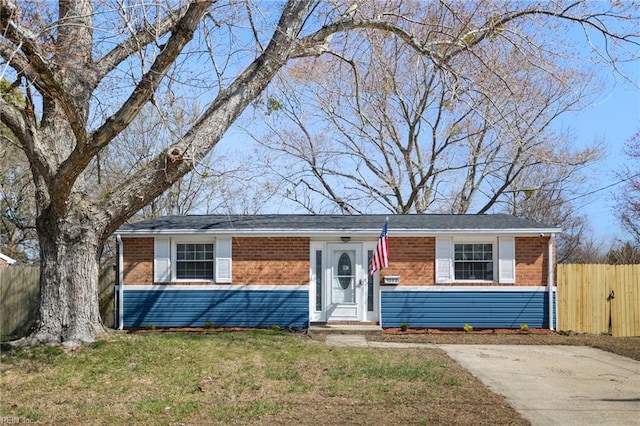 ranch-style house with a front yard, fence, and brick siding