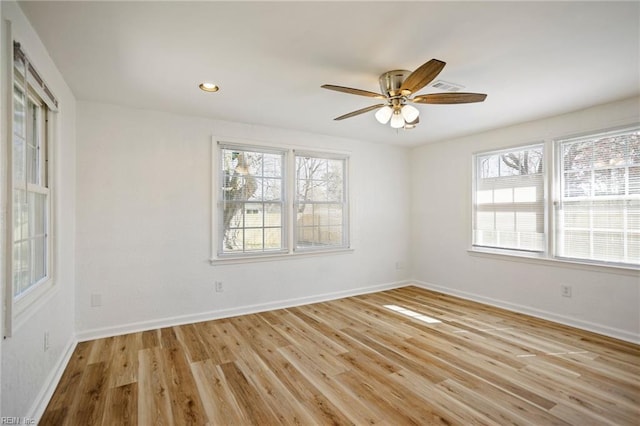 spare room featuring light wood finished floors, plenty of natural light, a ceiling fan, and baseboards