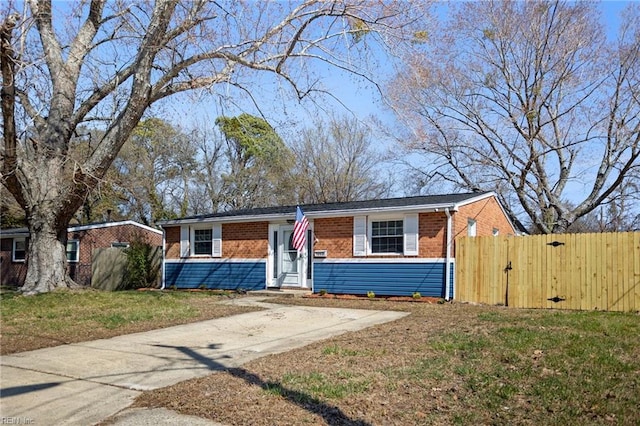 view of front of property with a gate, brick siding, a front yard, and fence