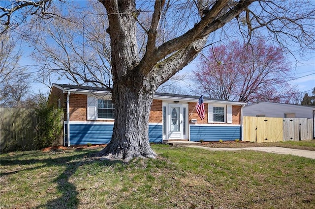 view of front of property with a front lawn, a gate, fence, and brick siding